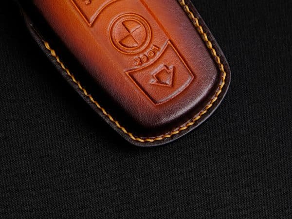 Cận cảnh đường khâu tay trên bao da chìa khóa BMW Z4, chỉ vàng nổi bật.