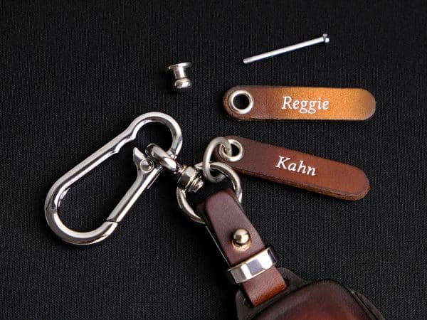 Bao da chìa khóa BMW XM gồm thẻ tag khắc tên và móc khóa đi kèm.