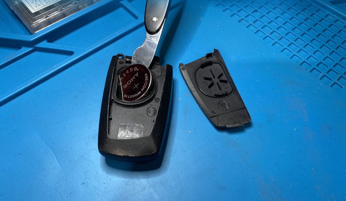 Kỹ thuật viên đang dùng lẫy khóa cơ bẩy nhẹ nắp lưng chìa khóa BMW