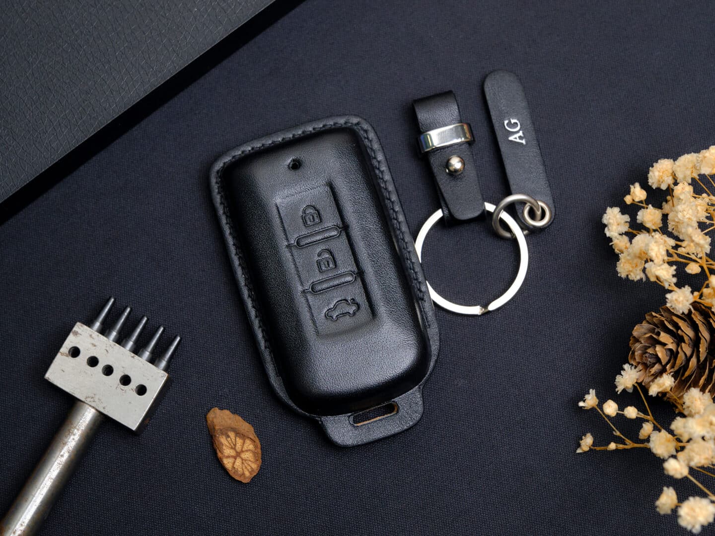 Bao da chìa khóa Mitsubishi handmade đặt cạnh chìa thật trên bàn da thủ công
